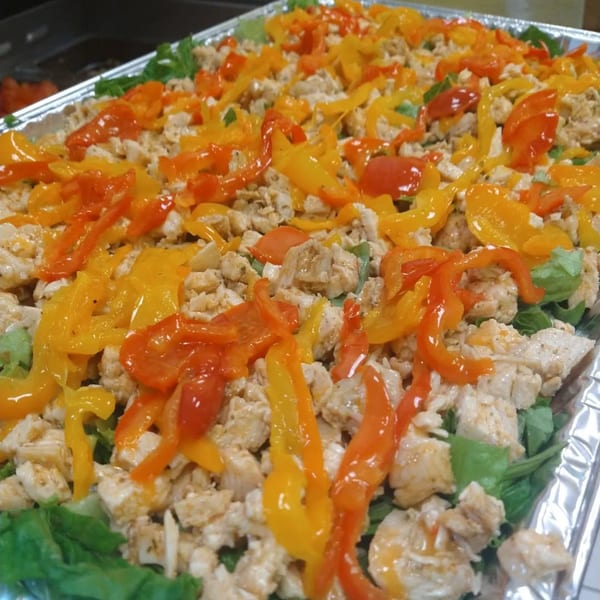 A catering tray filled with theBESTdamnsalad's healthy chicken and bell pepper salad.